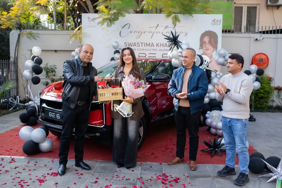 Cabinet Shrestha, left, handing a gift basket to Swastima Khadka in front of a red BE 6